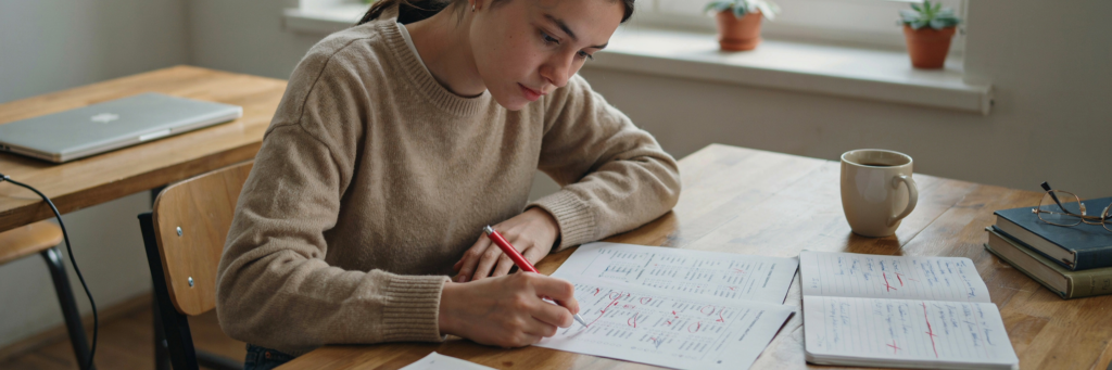 Étudiante corrigeant un QCM et notant ses erreurs pour progresser en révision