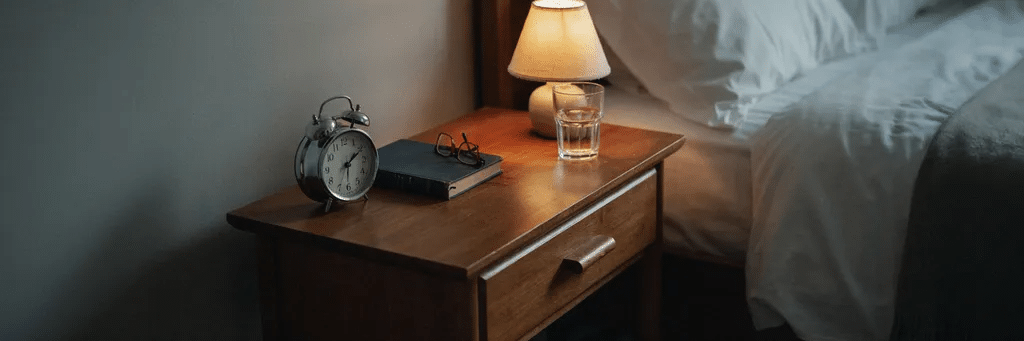 Chevet avec réveil et lampe tamisée, symbole d'un rythme de sommeil régulier